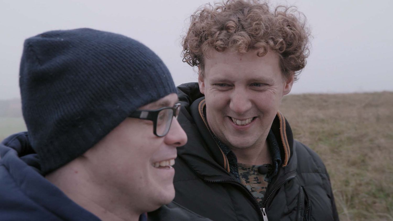 Jochem Myjer en Philippe Geubels lachen in de duinen.